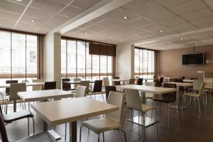 - une salle à manger avec des tables, des chaises et des fenêtres dans l'établissement Hôtel Limouzi Tulle Centre, à Tulle