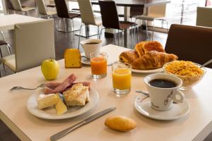 una mesa con dos platos de desayuno y zumo de naranja en Hôtel Limouzi Tulle Centre, en Tulle