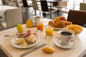 a table with two plates of breakfast foods and orange juice at Hôtel Limouzi Tulle Centre in Tulle