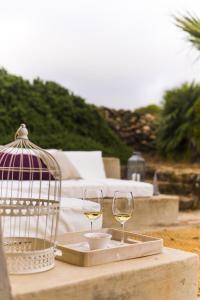 une table avec deux verres de vin blanc et une cage pour oiseaux dans l'établissement Dammuso Sant'Anna, à Pantelleria