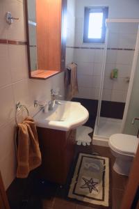 W łazience znajduje się umywalka, toaleta i lustro. w obiekcie Blue Harmony Villas w mieście Kiotari