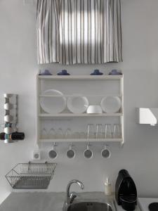 a kitchen counter with plates and cups and a sink at Sopravento House in Serifos Chora