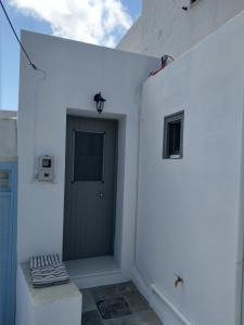 a white building with a green door and a window at Sopravento House in Serifos Chora