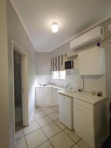 a kitchen with white cabinets and a tile floor at Loerie Guesthouse in Hoedspruit