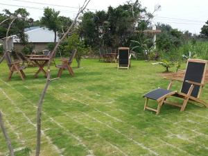 a yard with chairs and tables on the grass at Minshuku Myojoso in Yoron