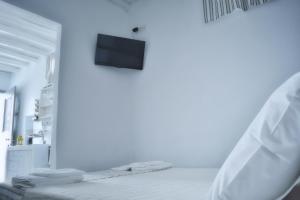 a white room with a bed and a tv on a wall at Sopravento House in Serifos Chora