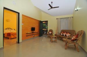 a room with a bed and a living room with a ceiling fan at Elegant Shades in Colva