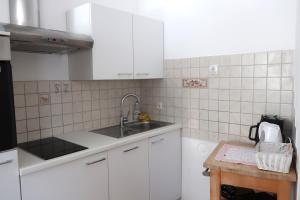 kuchnia z białymi szafkami, zlewem i stołem w obiekcie Apartment Maya w mieście Kranjska Gora