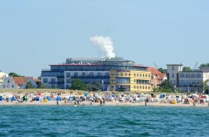a building on the beach with people on the beach at Strand-Hotel Hübner in Warnemünde