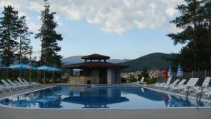 a swimming pool with chairs and a gazebo at Velingrad Balneohotel in Velingrad