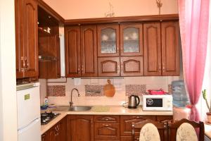 a kitchen with wooden cabinets and a sink and a microwave at Apartment on Shevchenka Boulevard in Ternopil
