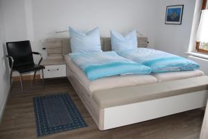 a bed with blue pillows and a chair in a room at Burbergblick in Schutz