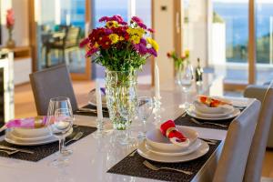 a table with plates and a vase of flowers on it at Bel Etage Amora Luxury Seaview Apartment with pool in Split +39 photos