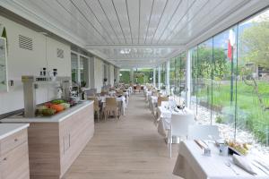 a restaurant with white tables and chairs and large windows at Al Brenta in Levico Terme