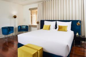 um quarto com uma grande cama branca com almofadas amarelas em Convento do Seixo Boutique Hotel & Spa no Fundo