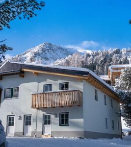 a house in the snow with a mountain in the background at Ferienwohnung Schneehase in Turracher Hohe
