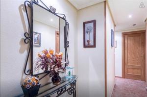 einen Spiegel an der Wand mit einer Vase Blumen auf dem Tisch in der Unterkunft RUMOHOLIDAYS Spacious 3 bedrooms apartment Playa del Cura in Torrevieja