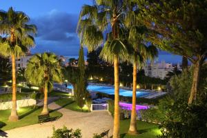 - une vue sur la piscine bordée de palmiers la nuit dans l'établissement Vila Petra, à Albufeira