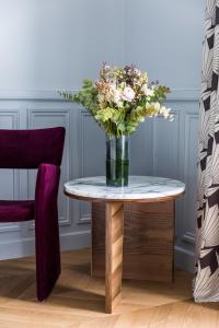a vase of flowers on a table next to a chair at Grand Powers Hotel in Paris