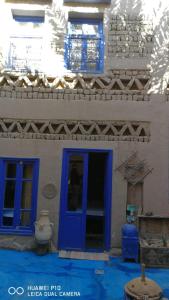 eine blaue Tür in einem weißen Gebäude mit blauem Boden in der Unterkunft Chez Youssef in Merzouga