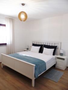een slaapkamer met een groot wit bed en een blauwe deken bij Apartmani Lavanda in Vrsi