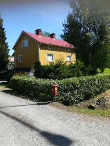 a yellow house with a red roof on a street at Koskentien kotimajoitus in Jämsä