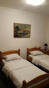 two beds in a room with a painting on the wall at Motel Jelčić in Čapljina