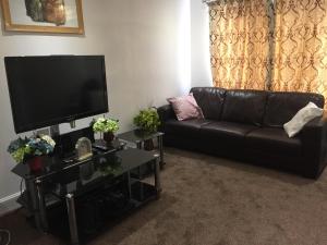 Una sala de estar con un sofá de cuero negro y un televisor de pantalla plana. en Alphalink Lodge, en Middlesbrough
