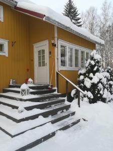 a house with snow on the stairs in front of it at Koskentien kotimajoitus in Jämsä