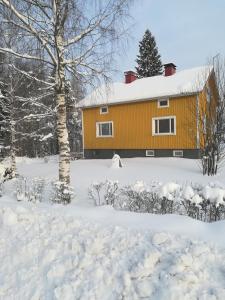una casa gialla nella neve con un cortile di Koskentien kotimajoitus a Jämsä