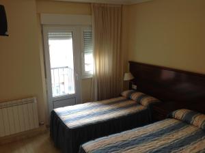 um quarto de hotel com duas camas e uma janela em Hostal San Froilan em La Virgen del Camino