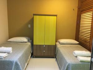 two beds in a room with a yellow cabinet at In Mare Bali Resort 127 in Parnamirim