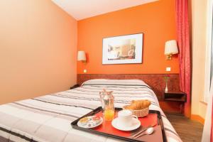 パリにあるオテル ピエール ニコールのベッドに食料品のトレイを用意したホテルルーム