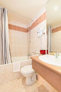 a bathroom with a toilet and a sink and a tub at Hotel Pierre Nicole in Paris