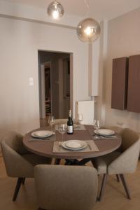 a dining room table with two chairs and a bottle of wine at Stylish Zoi's appartment next to HELEXPO, White Tower in Thessaloniki