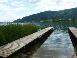 a dock on a lake with mountains in the background at Seeapartments Kärnten in Bodensdorf