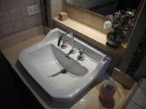lavabo blanco en el baño con espejo en Entre Sierras B&B en Tandil