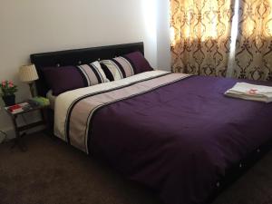 a bedroom with a large bed with purple sheets and pillows at Alphalink Lodge in Middlesbrough