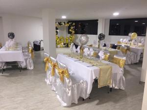 a room with white tables with yellow bows at Hotel Engatama in Moniquirá
