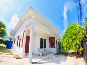 a white house with a chair and a fence at The Endless Bangtao Residence TV2 AND TV 3 in Bang Tao Beach