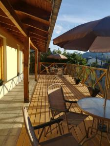 una terraza con sillas, mesas y sombrilla en Los Saucos en El Hoyo