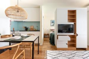 a kitchen and living room with a table and a television at The Foz Garden Studio in Porto