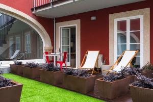 a row of chairs and tables on a patio with grass at The Foz Garden Studio in Porto