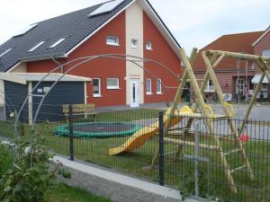 un parque infantil frente a una casa en Ferienhaus Seeschwalbe en Fehmarn