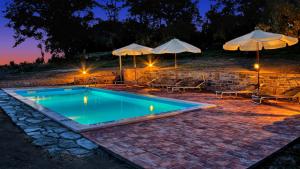 a swimming pool with umbrellas and tables and chairs at Rooms Agroturizam Romano in Buje