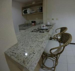 cocina con encimera de granito y 2 sillas en Flat Pipa's Ocean a passos da Praia e centro Pipa, en Pipa