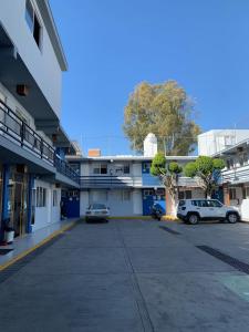 un estacionamiento con dos autos estacionados frente a un edificio en Hotel Tecnologico, en Querétaro
