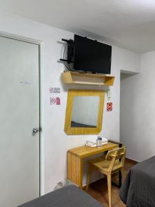 a bedroom with a desk with a mirror and a tv on the wall at Hotel Tecnologico in Querétaro