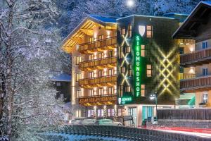ein Hotelgebäude mit einem grünen Schild im Schnee in der Unterkunft Hotel Garni Siegmundshof - inclusive Joker Card im Sommer in Saalbach-Hinterglemm