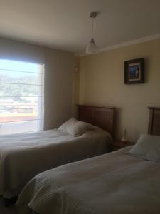 two beds in a hotel room with a window at Departamento 606 in Temuco